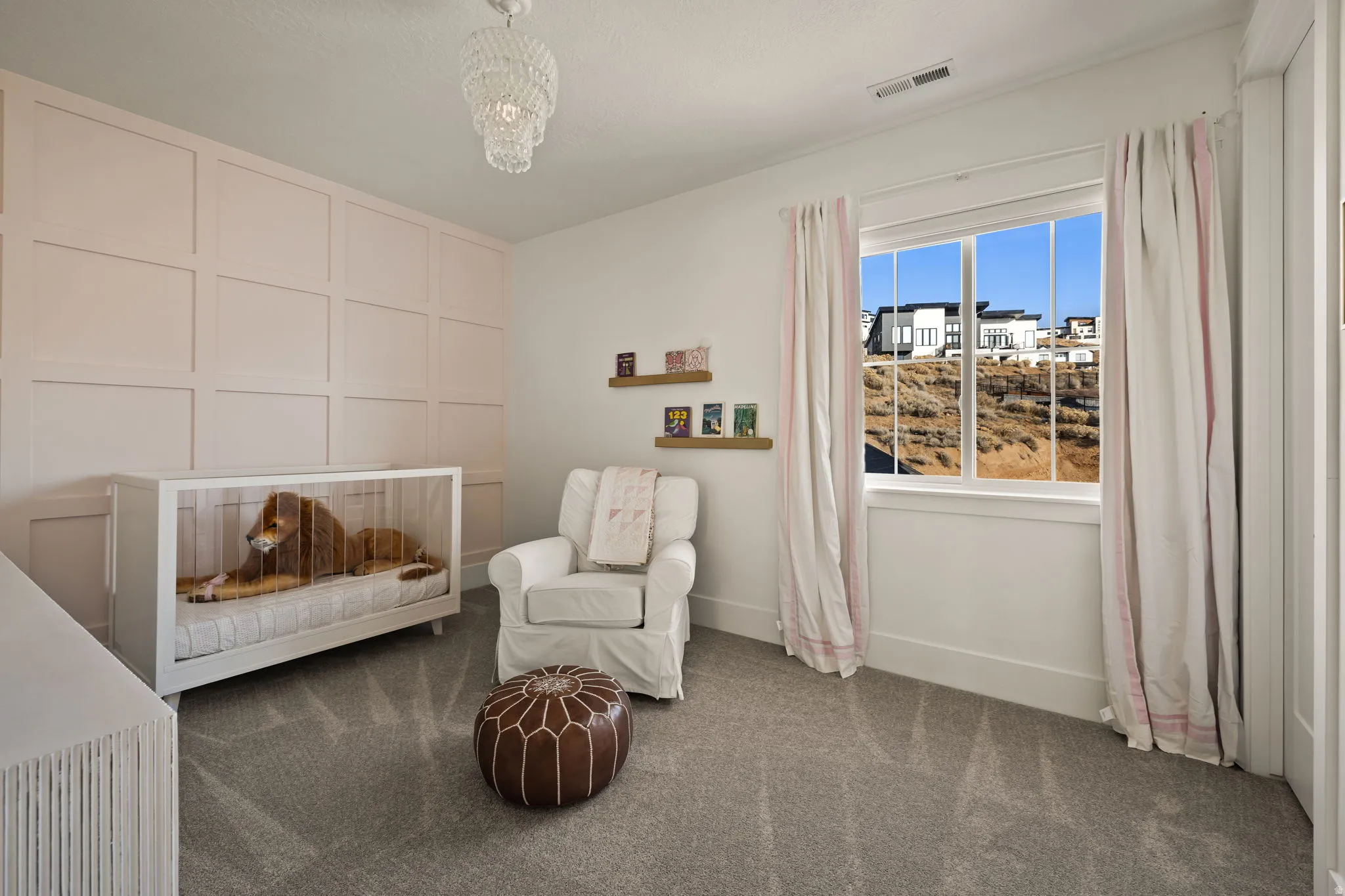 Bedroom featuring a decorative wall, carpet, a chandelier, and a crib