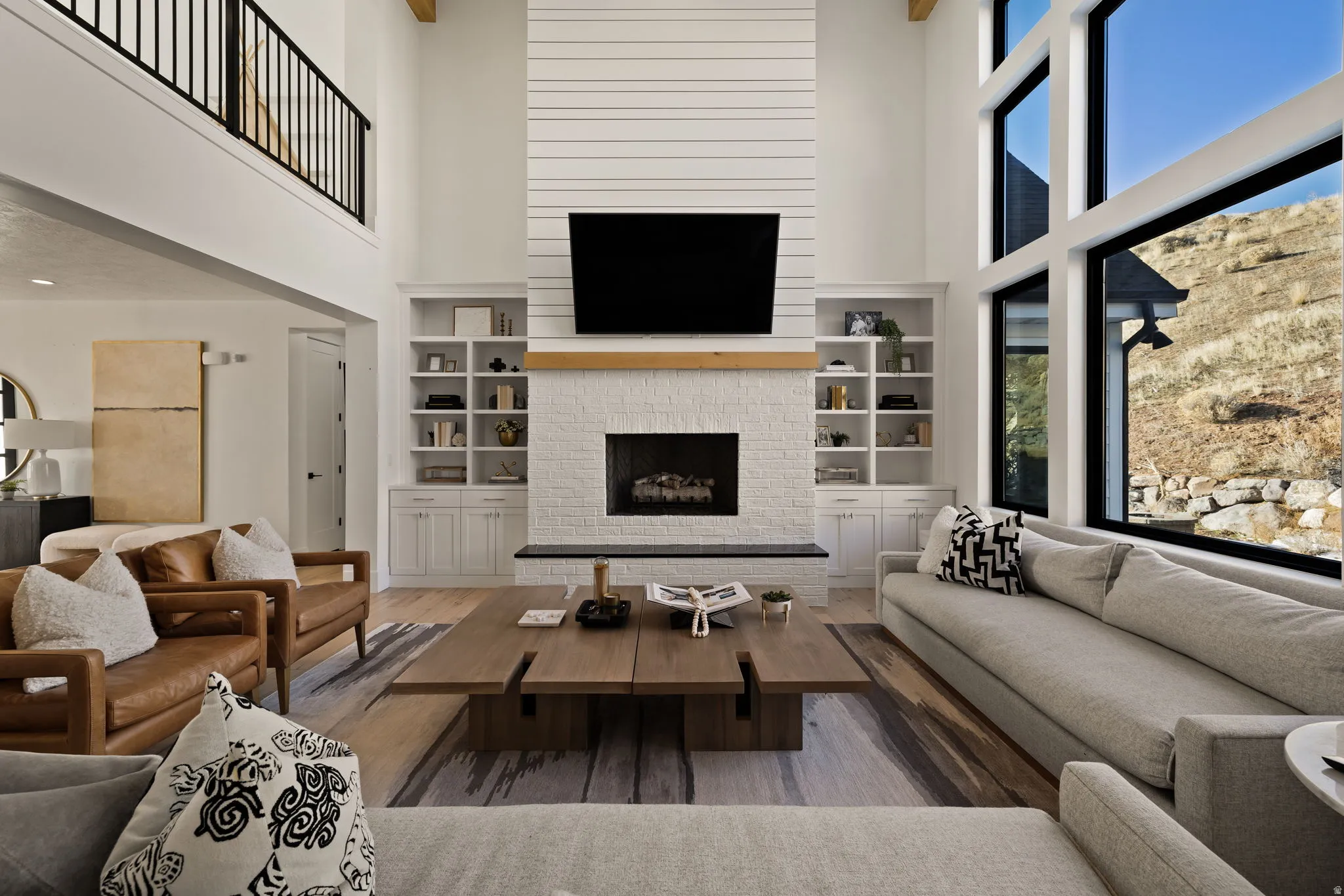 Living room featuring a towering ceiling, a fireplace, wood finished floors, and built in features