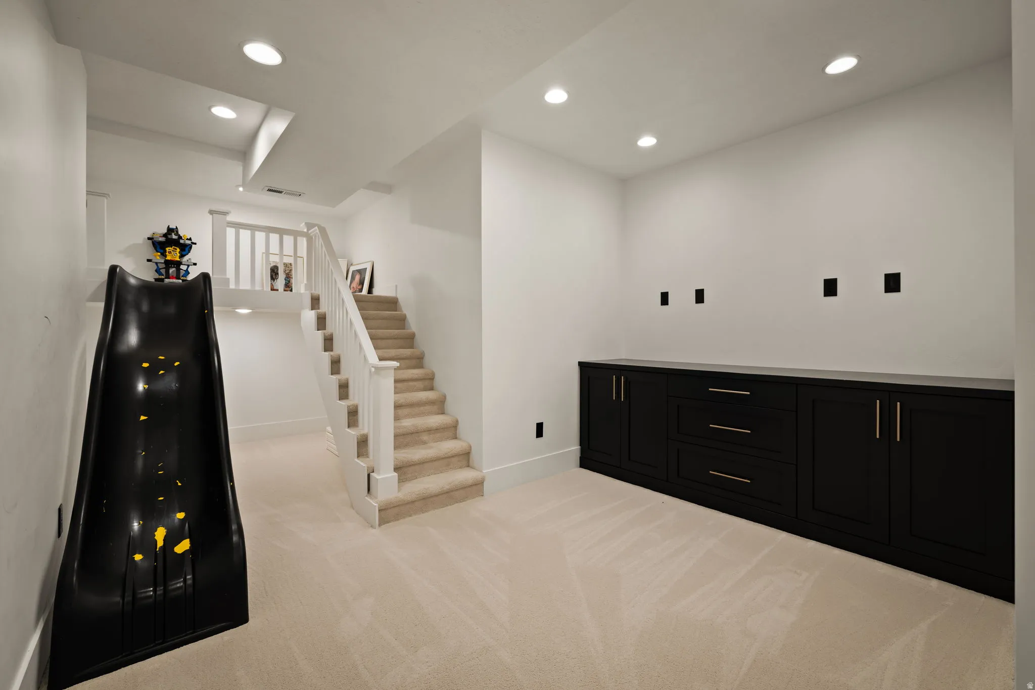 Bar area featuring dark cabinetry, recessed lighting, light carpet, and stairs