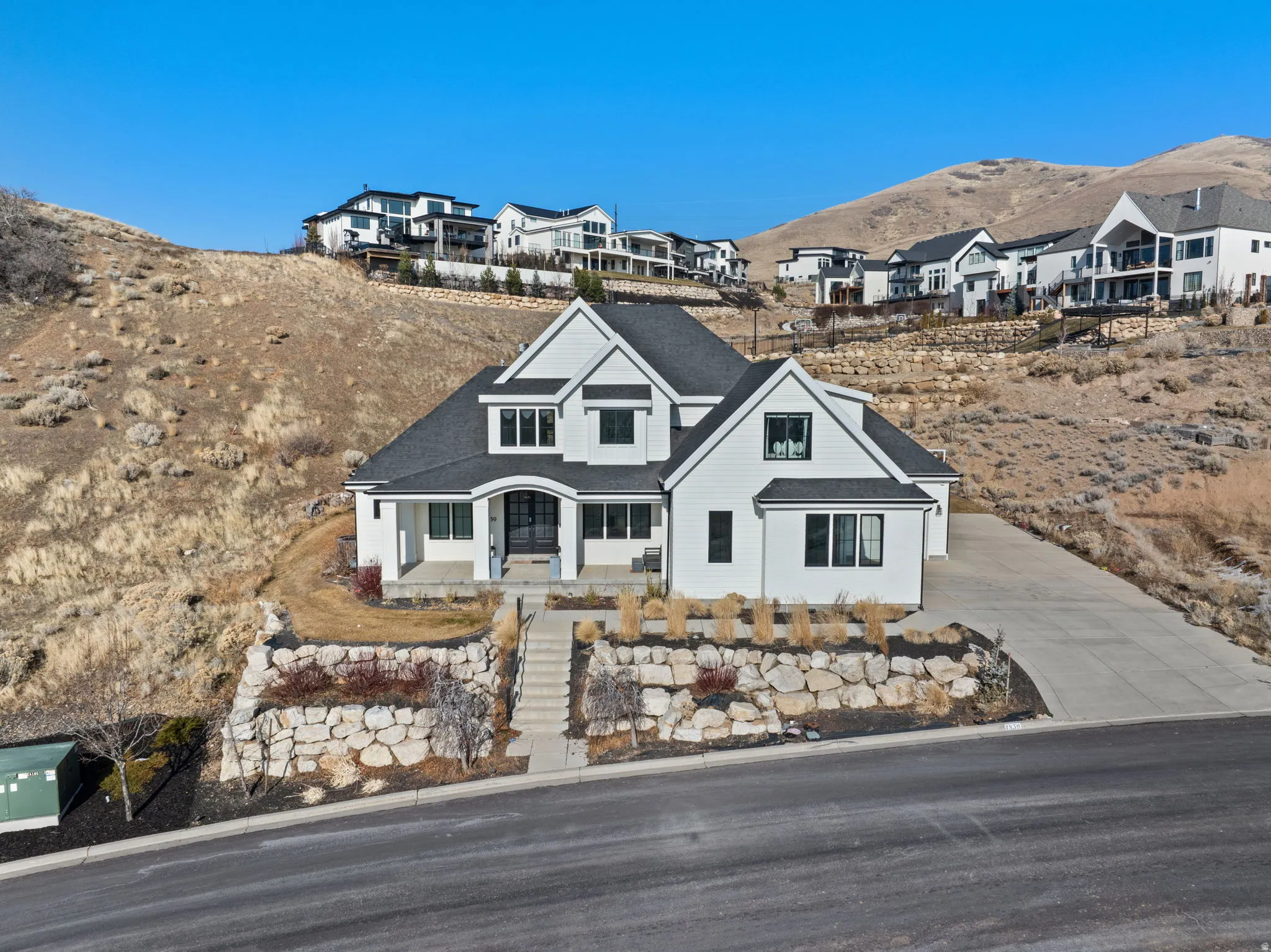 View of front of property with concrete driveway, a residential view, a mountain view, and stairs