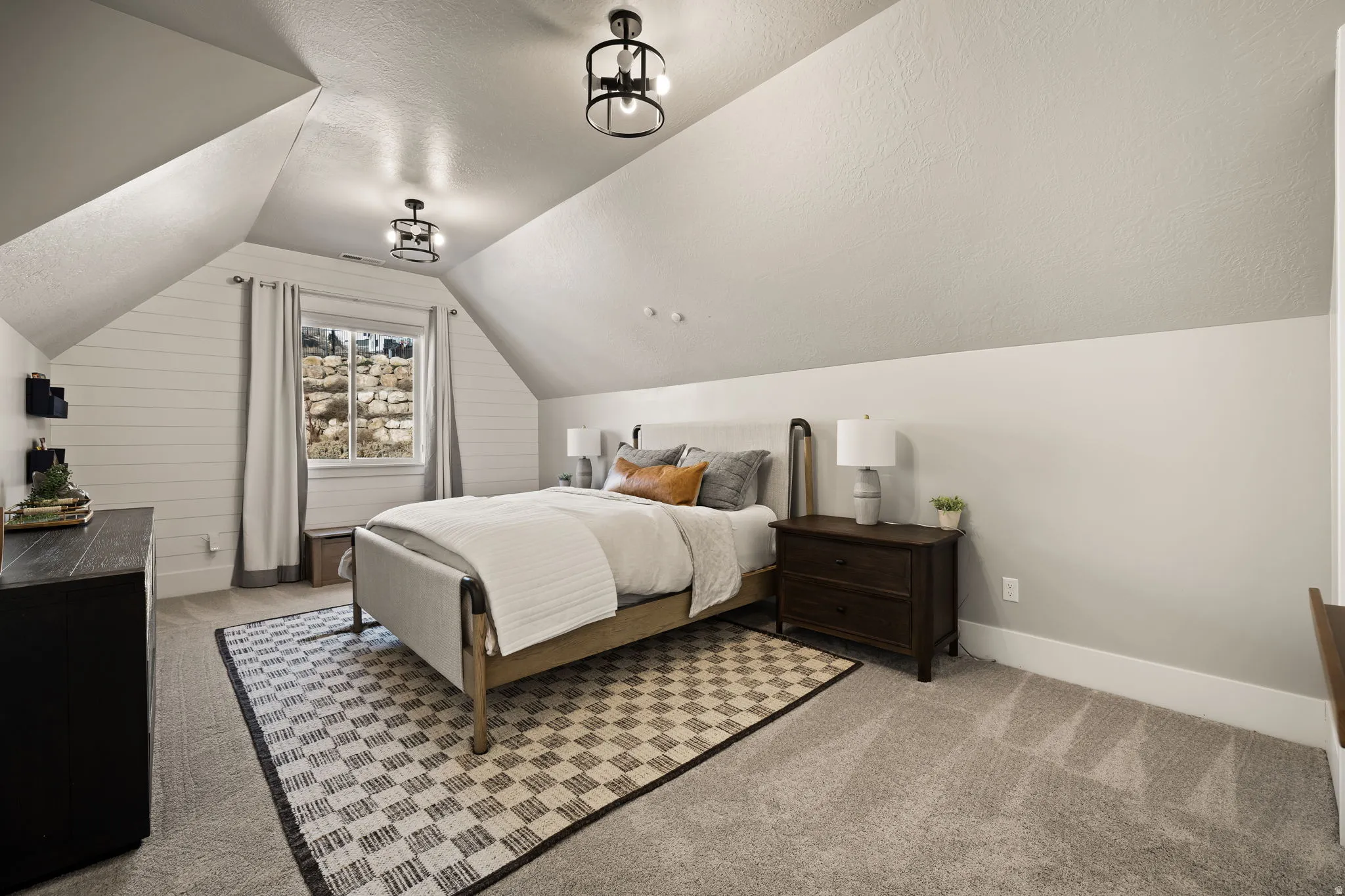Bedroom featuring lofted ceiling, light carpet, and a textured ceiling