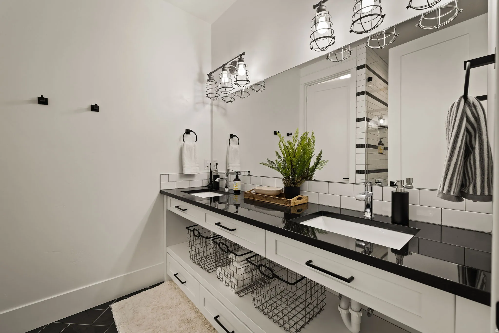 Bathroom with double vanity, backsplash, and dark tile patterned floors
