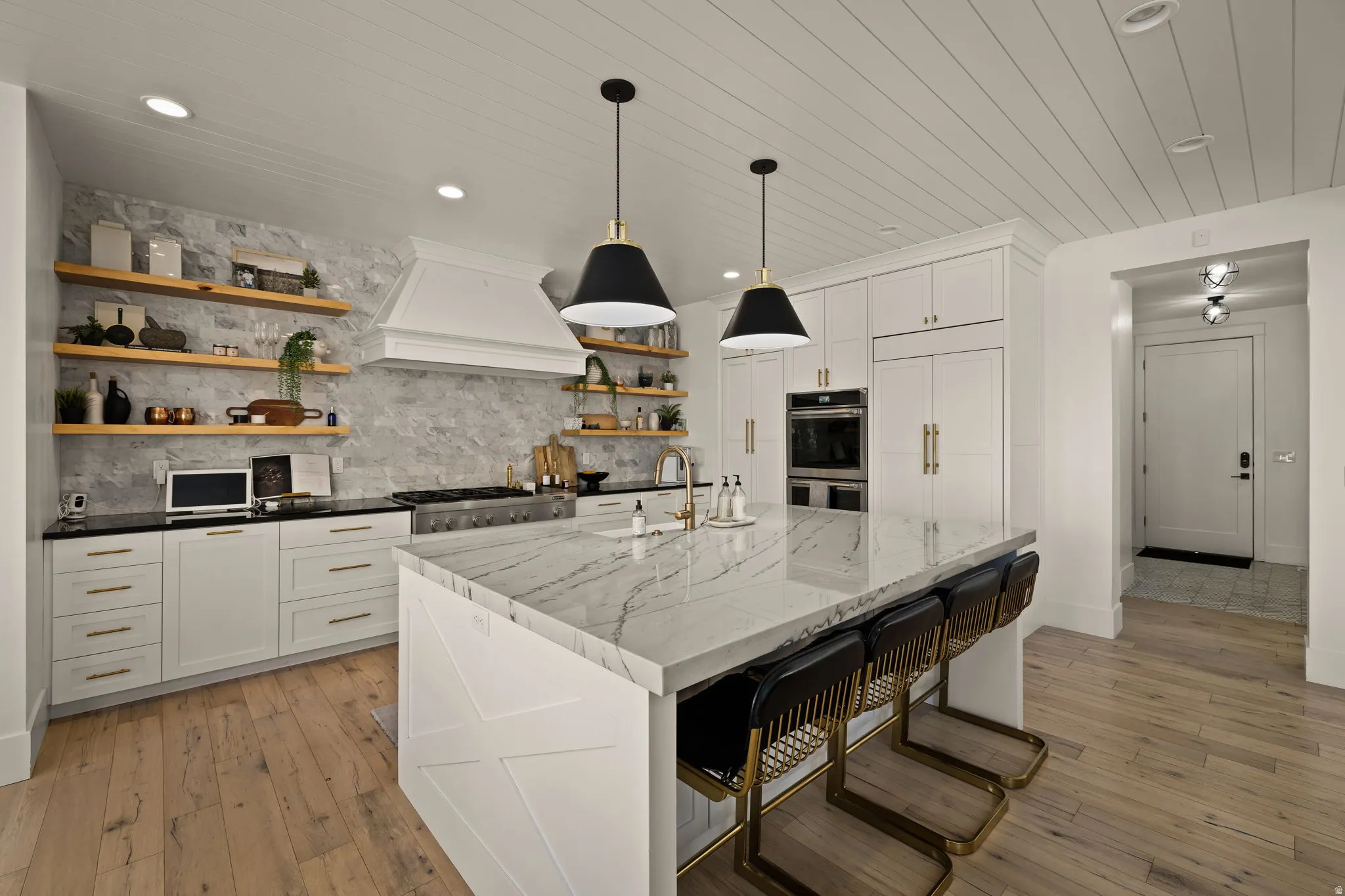 Kitchen with open shelves, white cabinets, a kitchen breakfast bar, backsplash, and dark stone counters