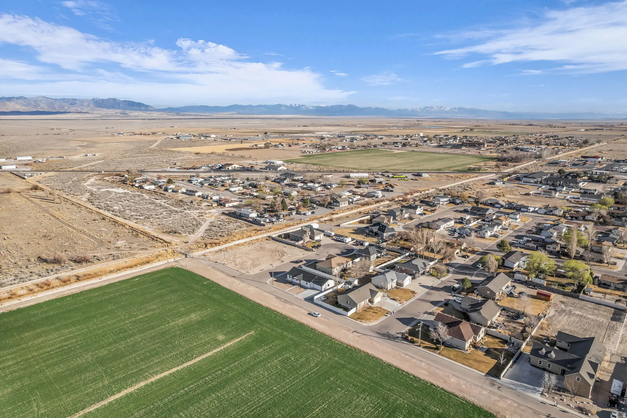 Overview of rural landscape featuring nearby suburban area and a mountainous background