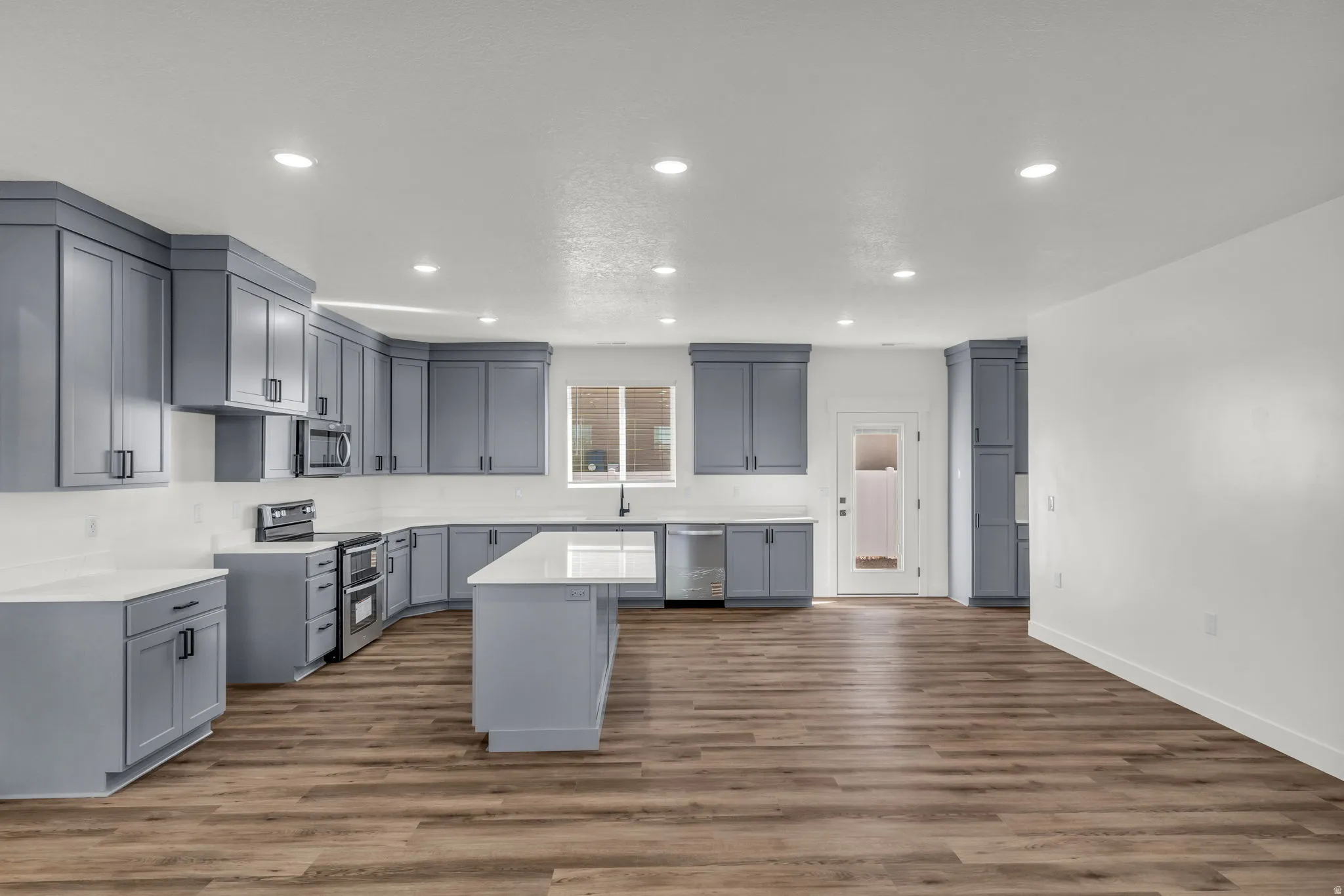 Kitchen with gray cabinets, a center island, dark wood-style flooring, recessed lighting, and stainless steel appliances
