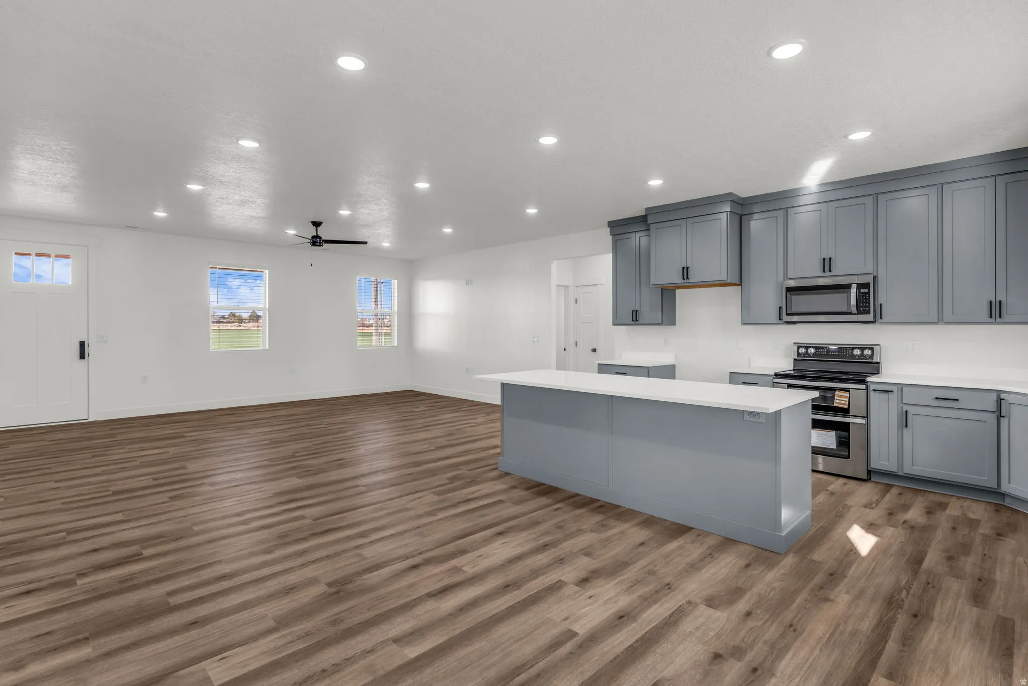 Kitchen featuring gray cabinetry, stainless steel appliances, recessed lighting, a kitchen island, and dark wood-style floors