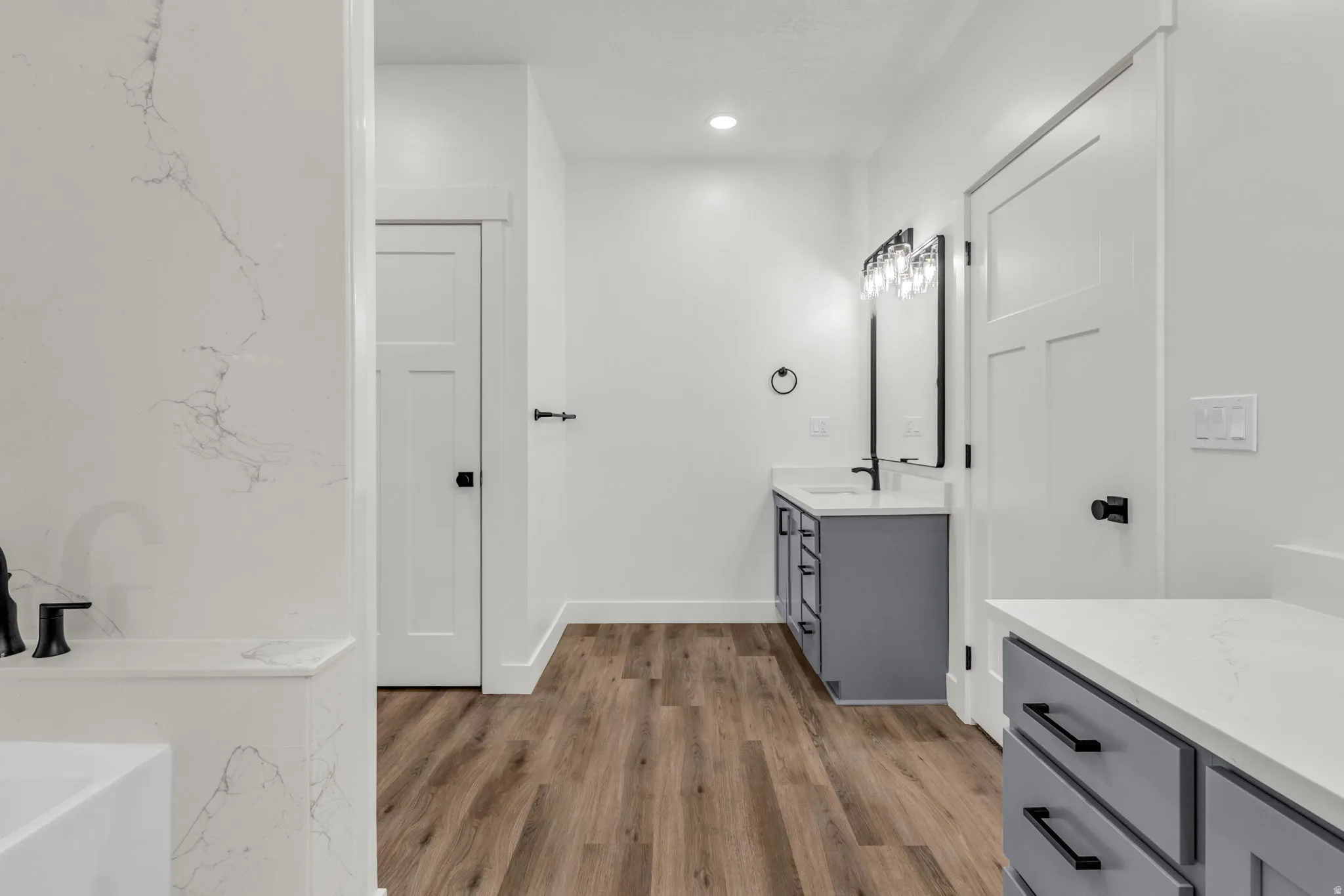 Bathroom with vanity, a soaking tub, light wood-type flooring, and recessed lighting