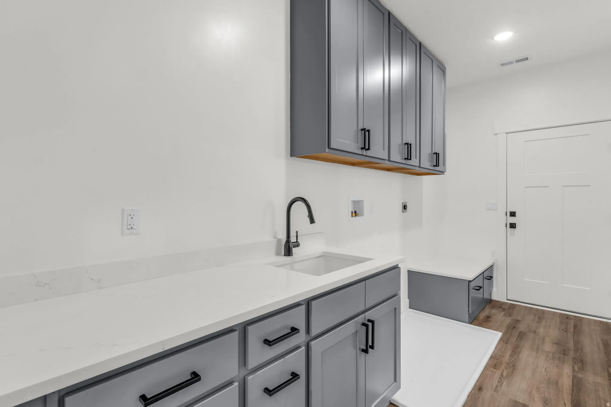 Laundry area featuring washer hookup, wood finished floors, cabinet space, and recessed lighting