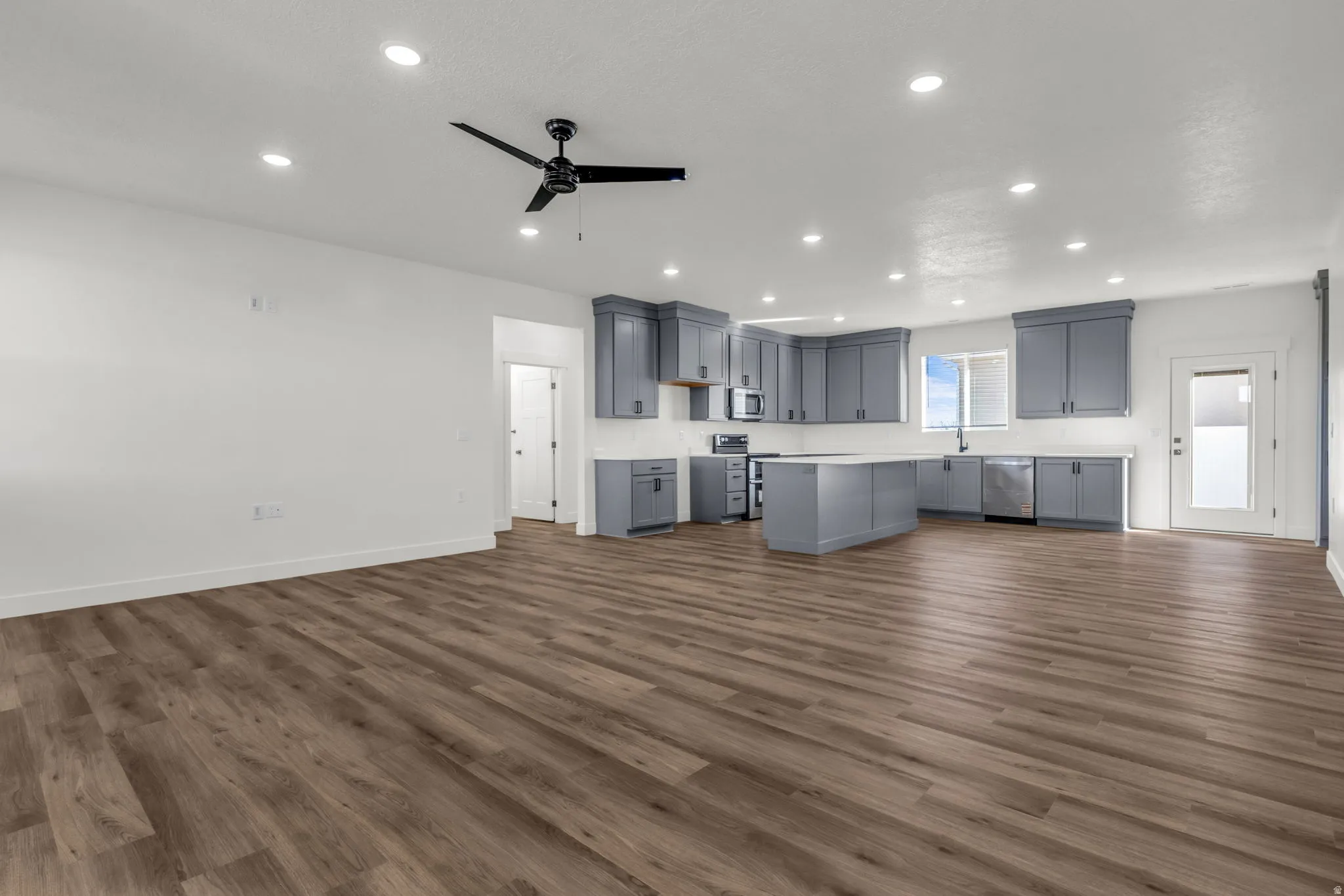 Kitchen with open floor plan, a ceiling fan, gray cabinetry, light countertops, and recessed lighting