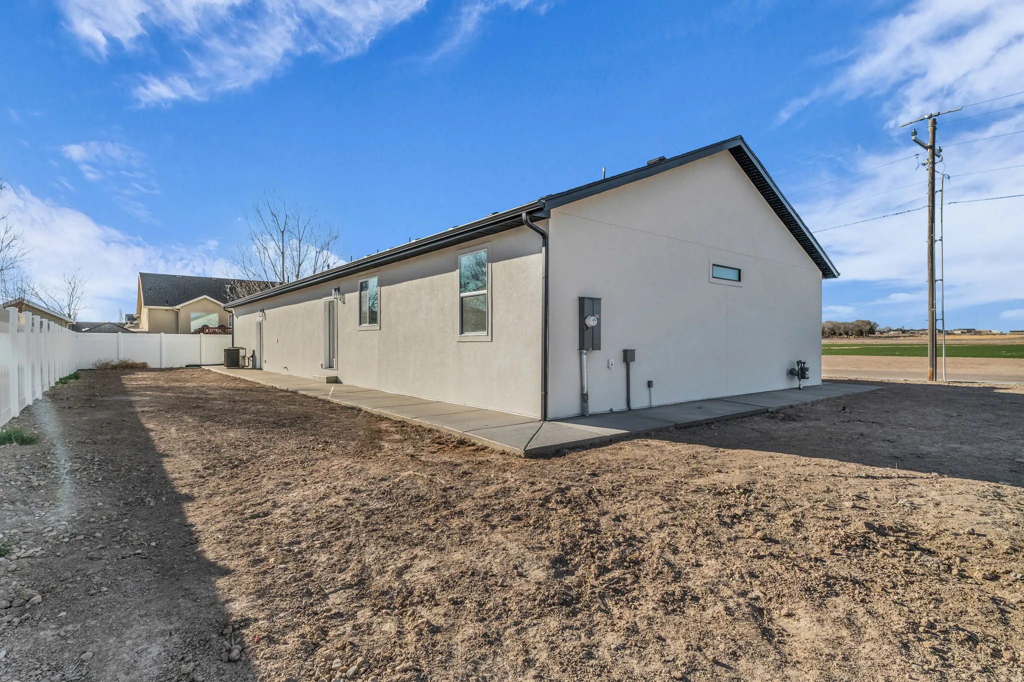 View of side of property featuring stucco siding, a fenced backyard, and a patio area
