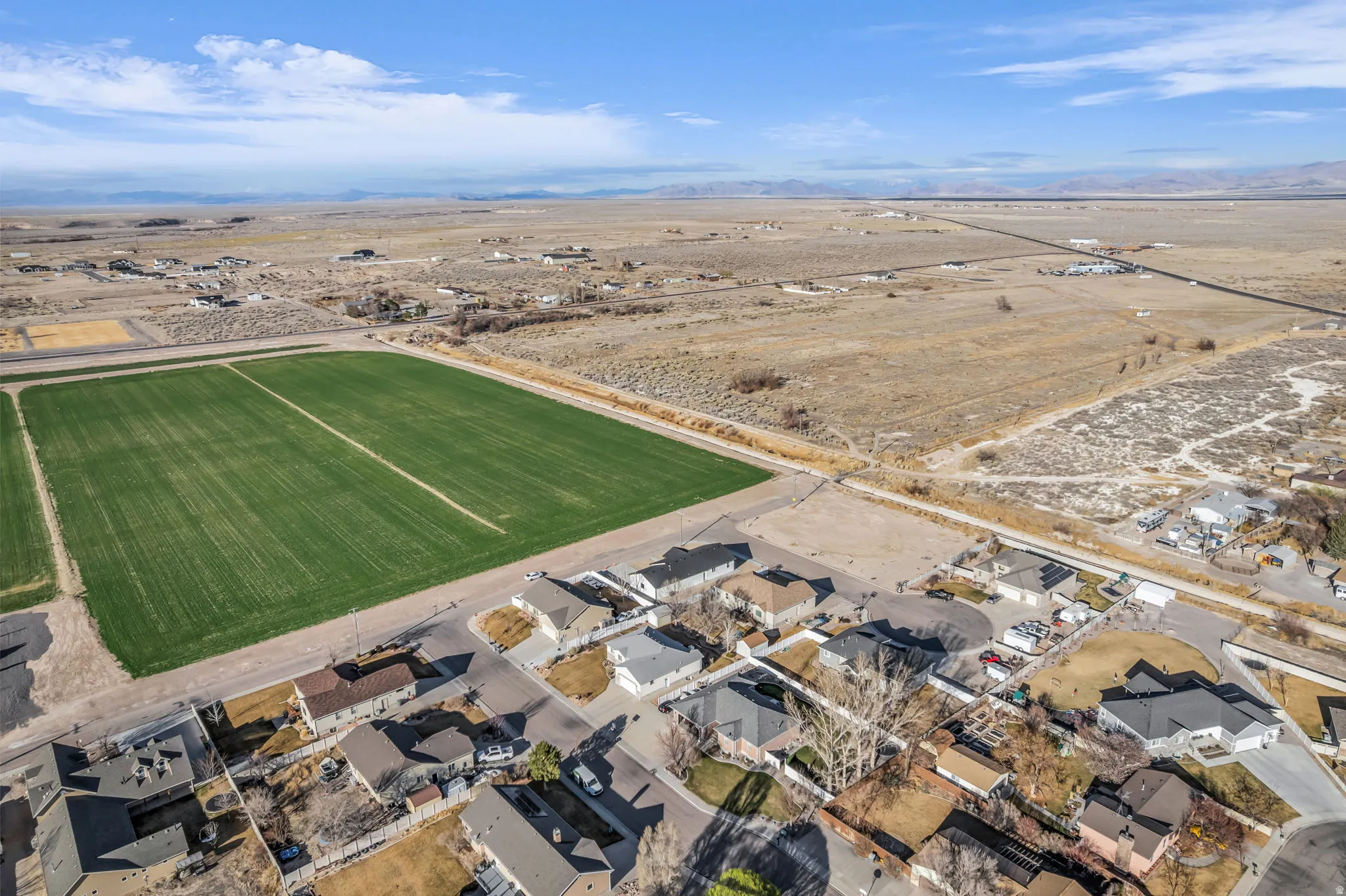 Aerial view of sparsely populated area featuring nearby suburban area and mountains