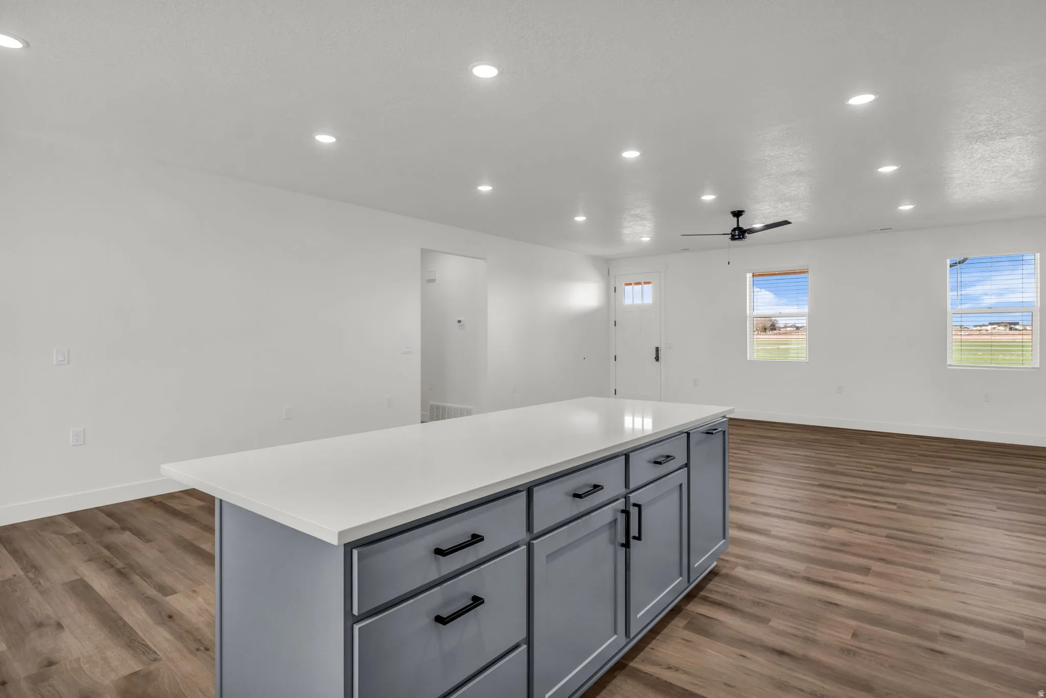 Kitchen featuring a center island, recessed lighting, open floor plan, gray cabinets, and dark wood-style floors