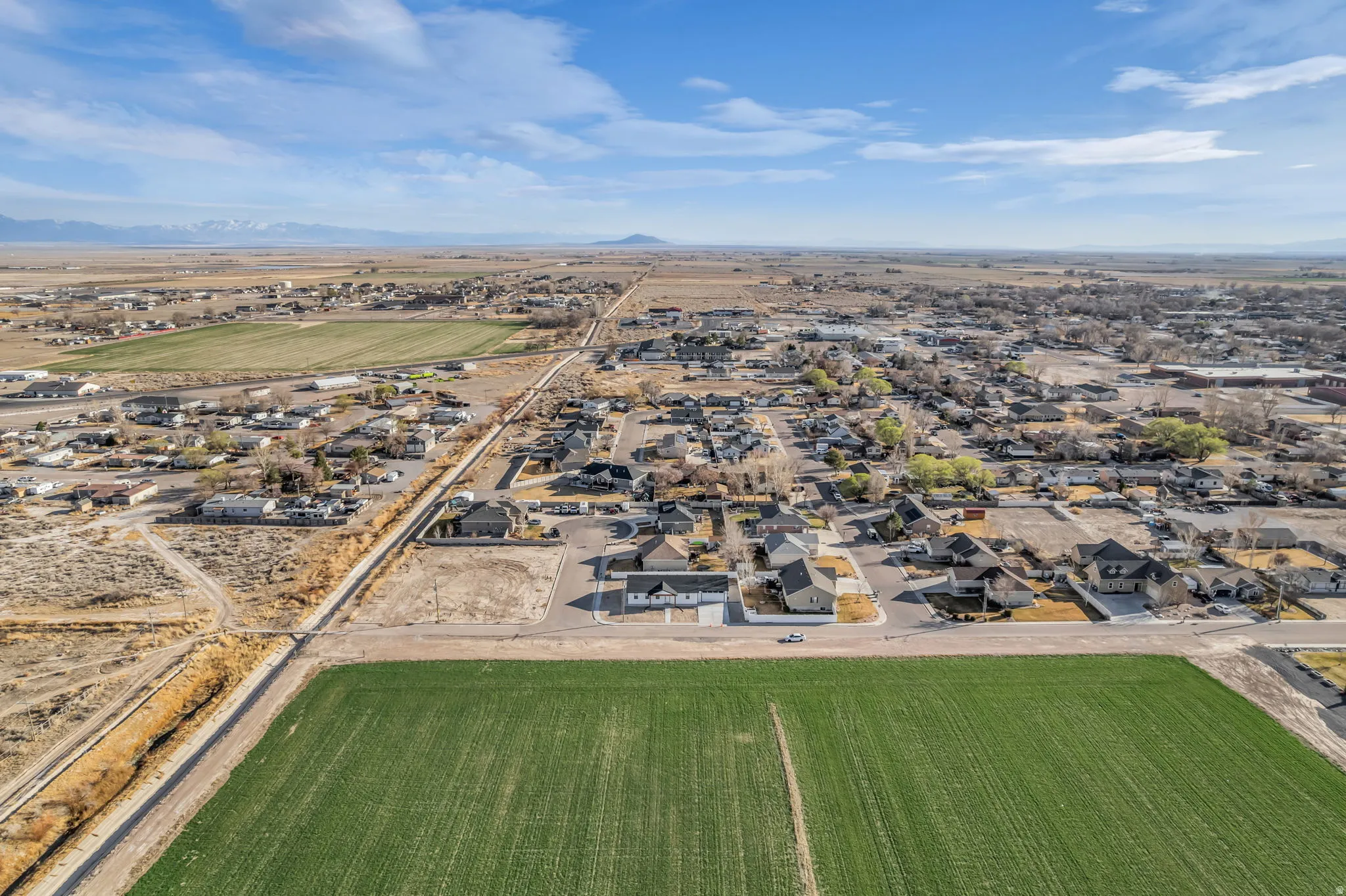 Overview of rural landscape featuring nearby suburban area and a mountainous background