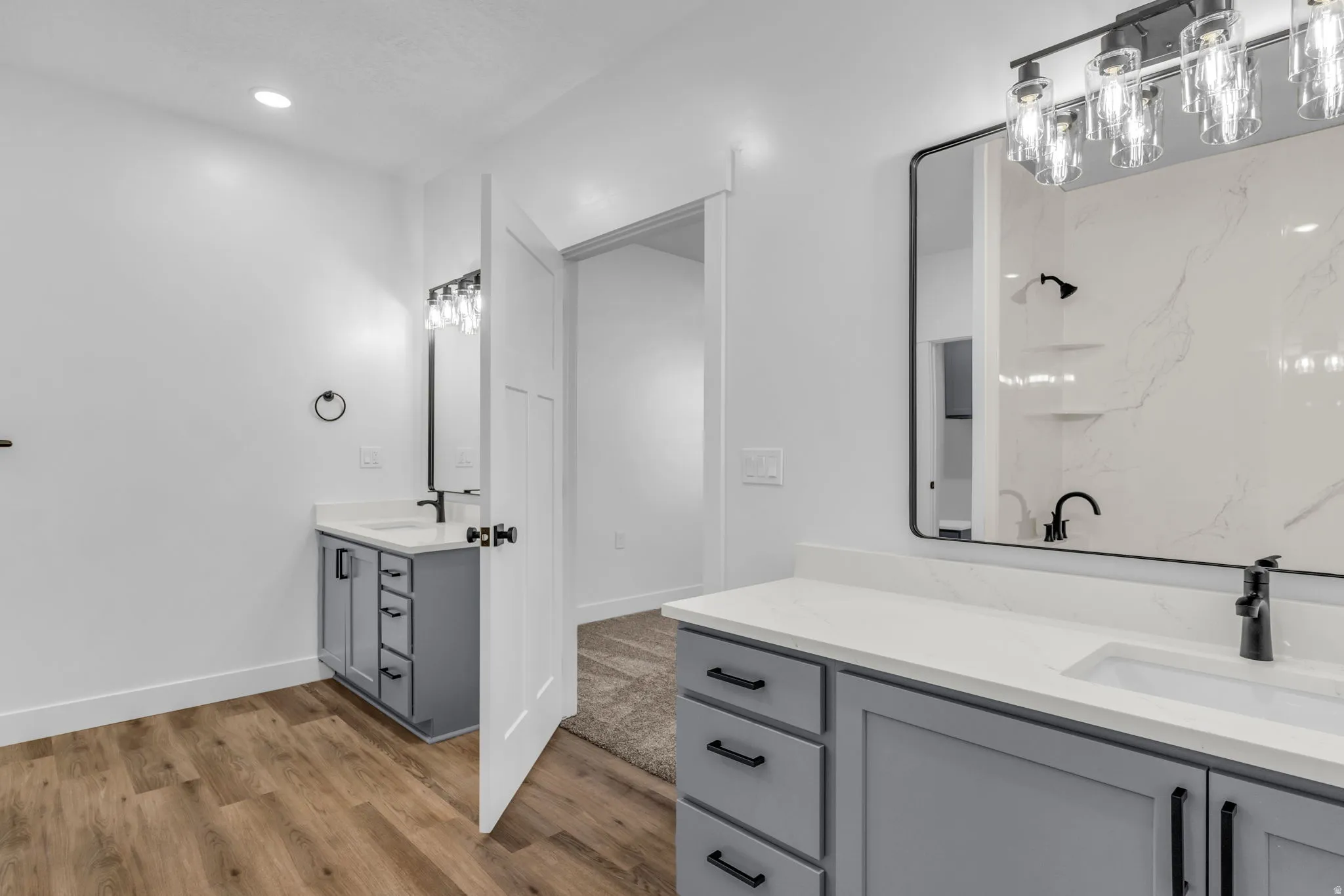 Full bathroom featuring two vanities, light wood-type flooring, and recessed lighting