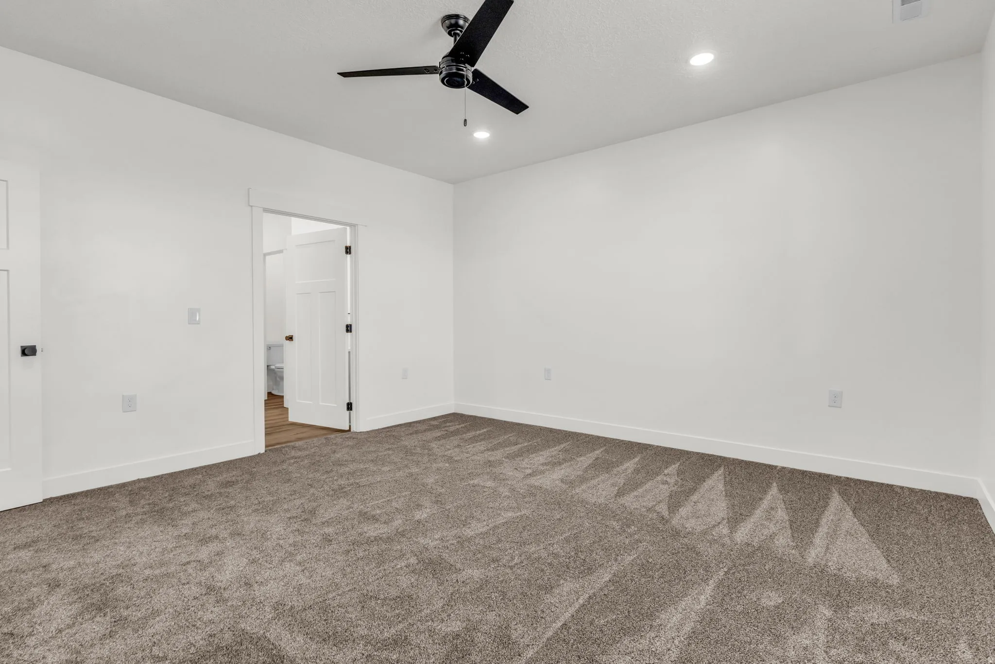 Unfurnished bedroom with dark colored carpet, ceiling fan, and recessed lighting