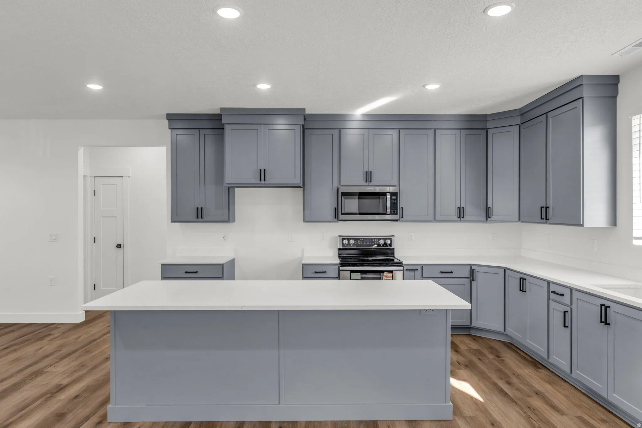 Kitchen with gray cabinetry, stainless steel appliances, dark wood-style floors, a kitchen island, and recessed lighting