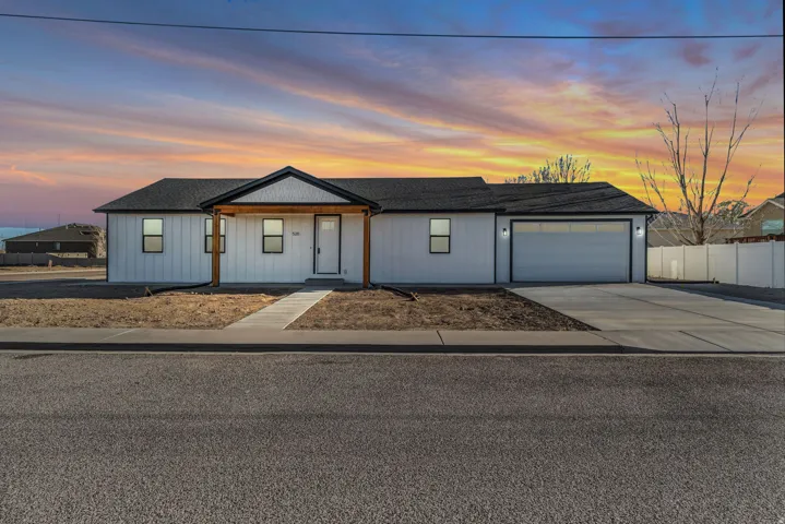 View of front of property featuring covered porch, an attached garage, driveway, and roof with shingles