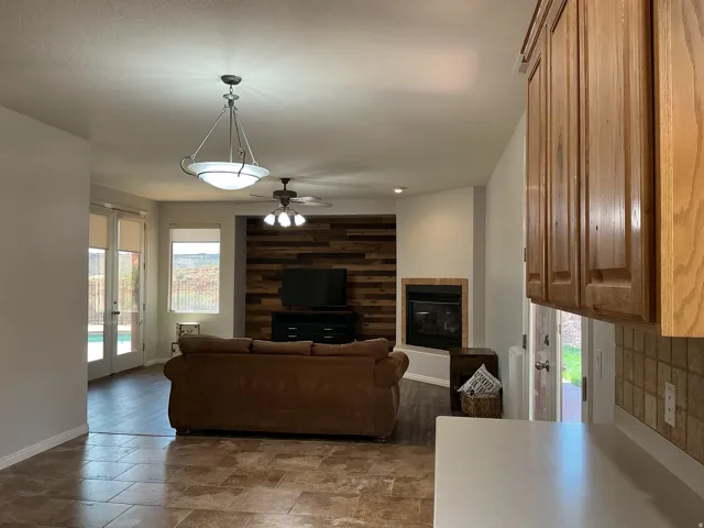 Living area with plenty of natural light, a ceiling fan, stone finish floors, a tile fireplace, and recessed lighting