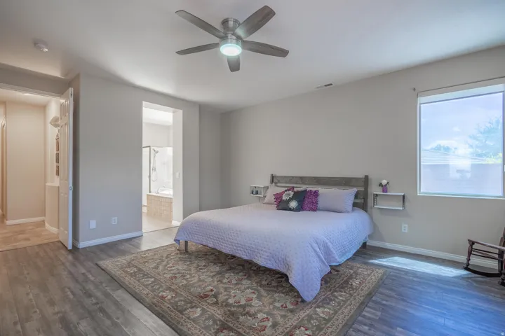 Bedroom featuring wood finished floors, a ceiling fan, and ensuite bathroom