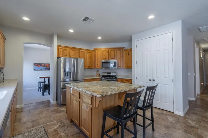 Kitchen featuring appliances with stainless steel finishes, a breakfast bar, brown cabinets, a kitchen island, and recessed lighting