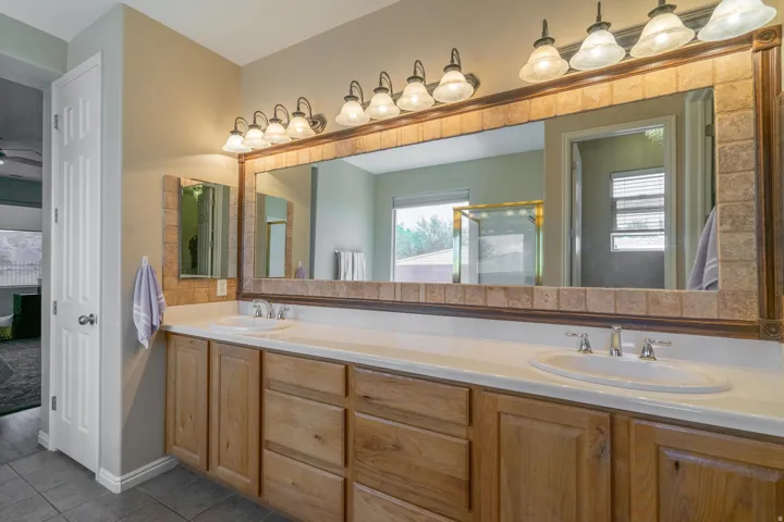 Ensuite bathroom featuring double vanity, tile patterned flooring, and a stall shower
