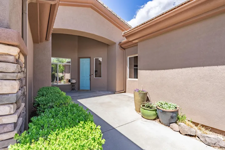 View of exterior entry featuring stucco siding and a patio area
