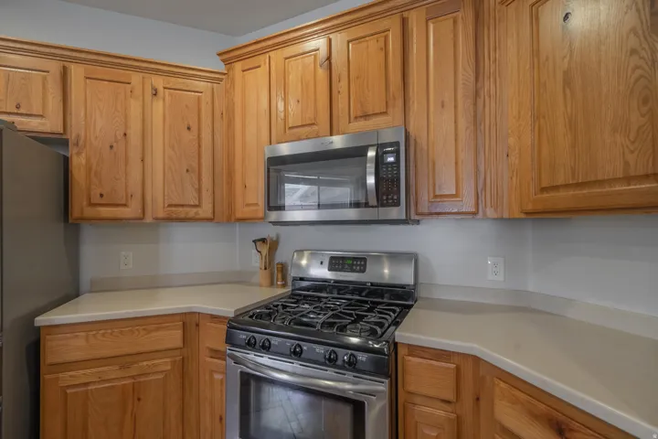Kitchen featuring stainless steel appliances, light countertops, and brown cabinets