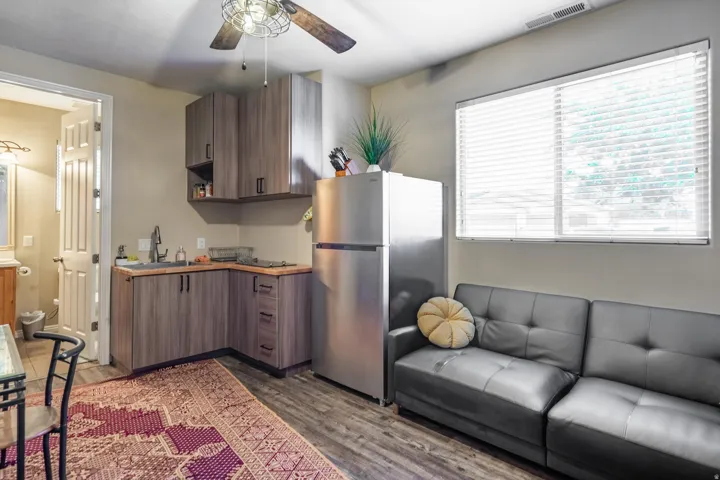 Kitchen with freestanding refrigerator, dark wood-style flooring, a ceiling fan, and open shelves