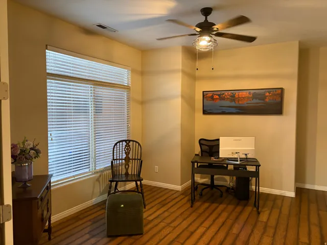 Office space with a ceiling fan and dark wood-style flooring