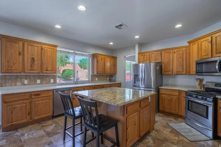 Kitchen with appliances with stainless steel finishes, brown cabinets, a breakfast bar area, a kitchen island, and recessed lighting