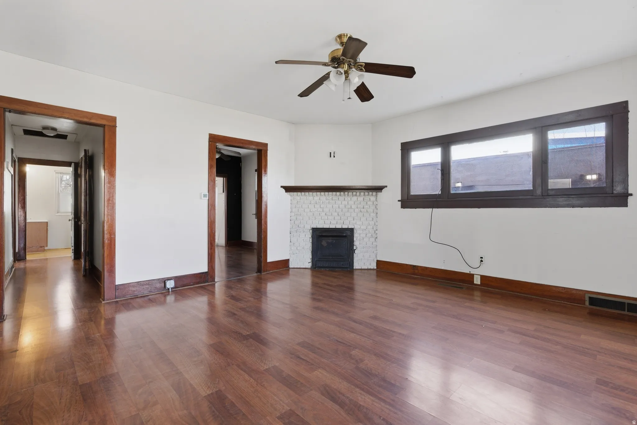 Unfurnished living room with dark wood-style floors, ceiling fan, and a fireplace