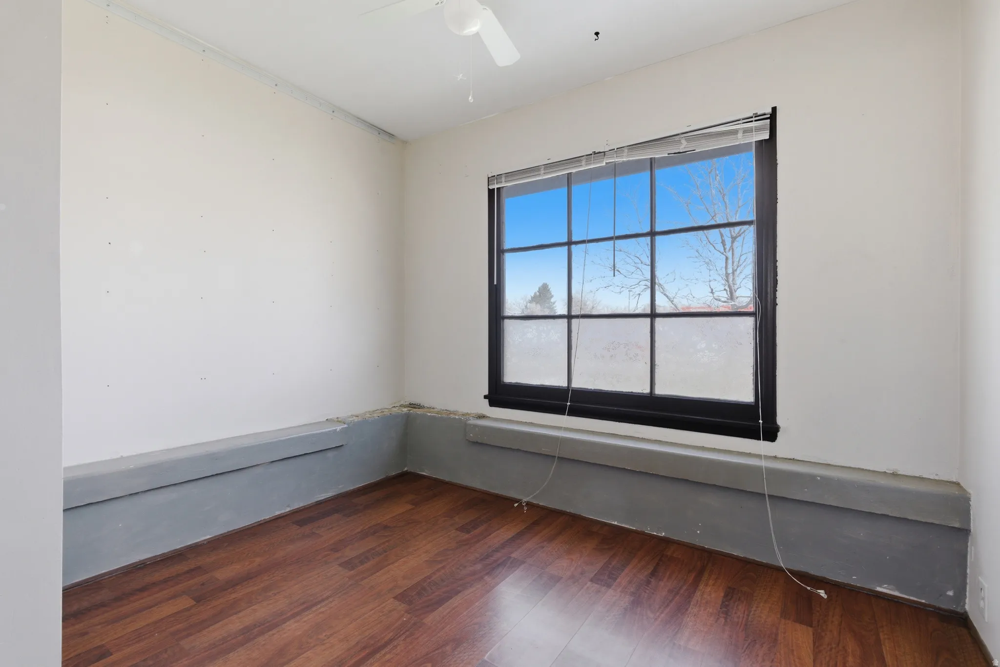 Spare room featuring dark wood-type flooring and a ceiling fan