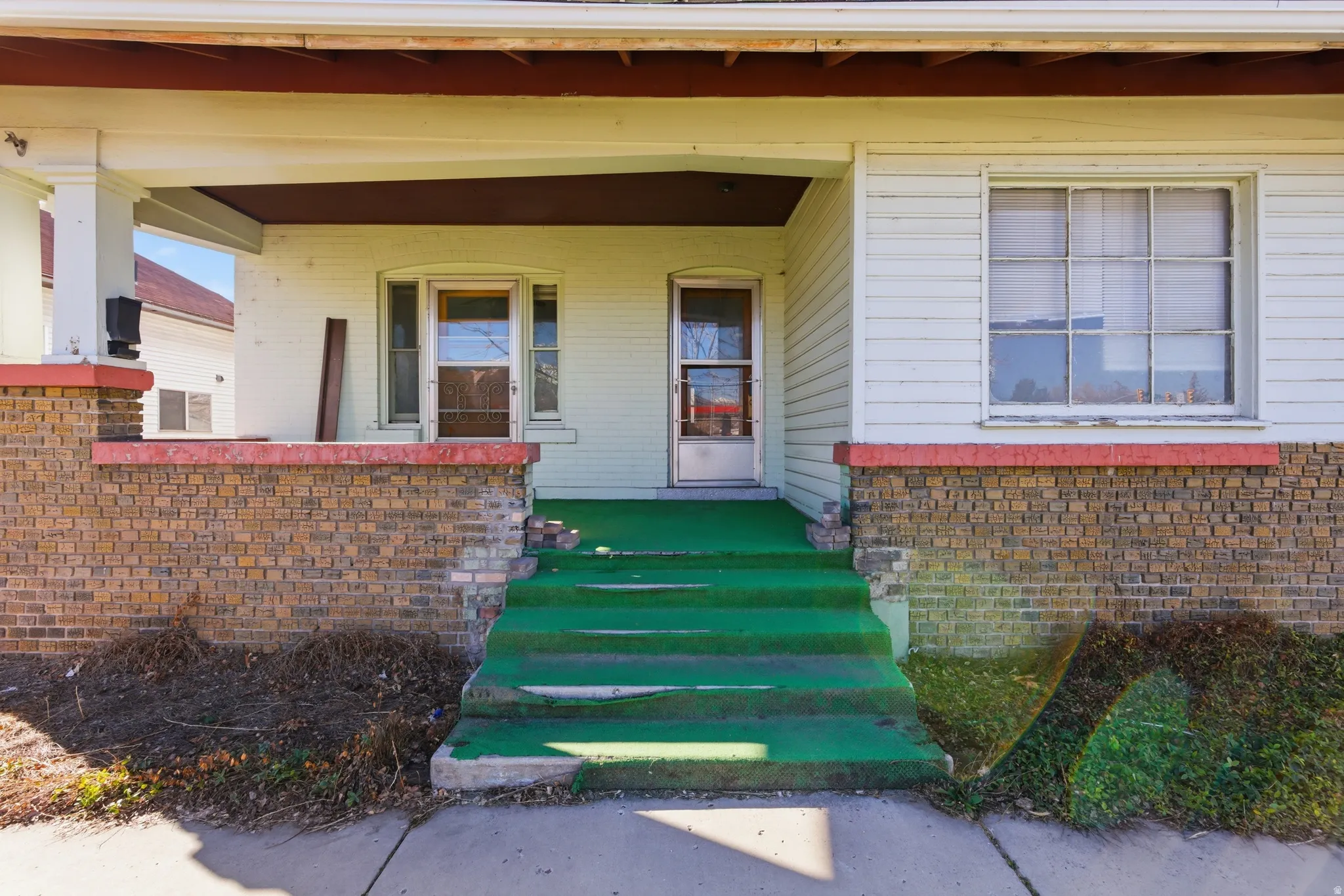 View of exterior entry featuring covered porch and brick siding