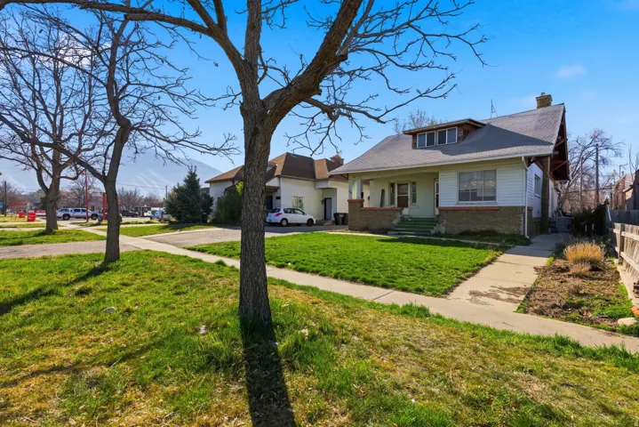 View of front of property with a chimney, brick siding, and a front yard