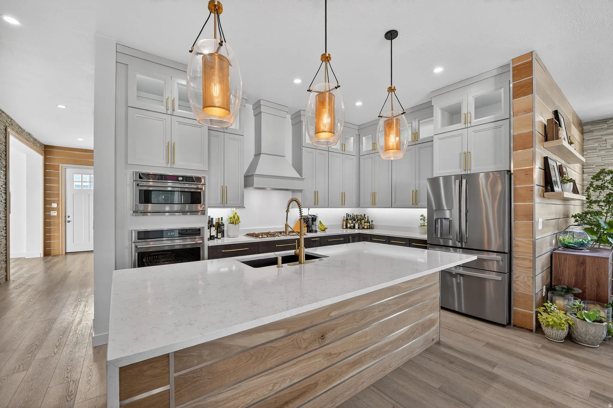 Chefs Kitchen with upgraded lighting, cabinets, wood accents and oversized waterfall granite island