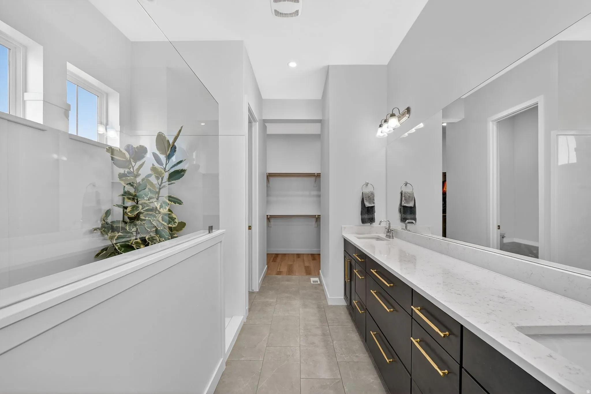Full bath featuring double vanity, a spacious closet, and walk in shower