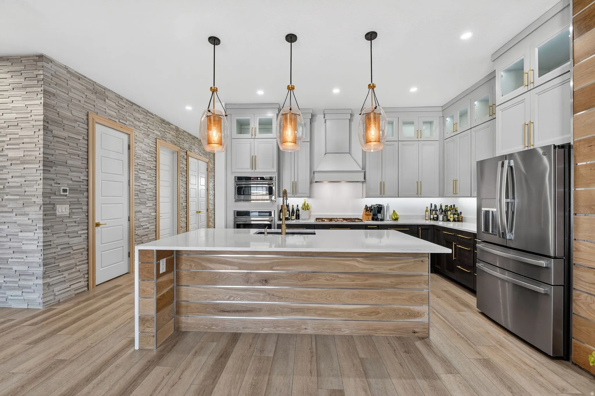 Kitchen featuring light granite countertops, decorative light fixtures, appliances with stainless steel finishes, recessed lighting, and custom range hood and water fall extended island
