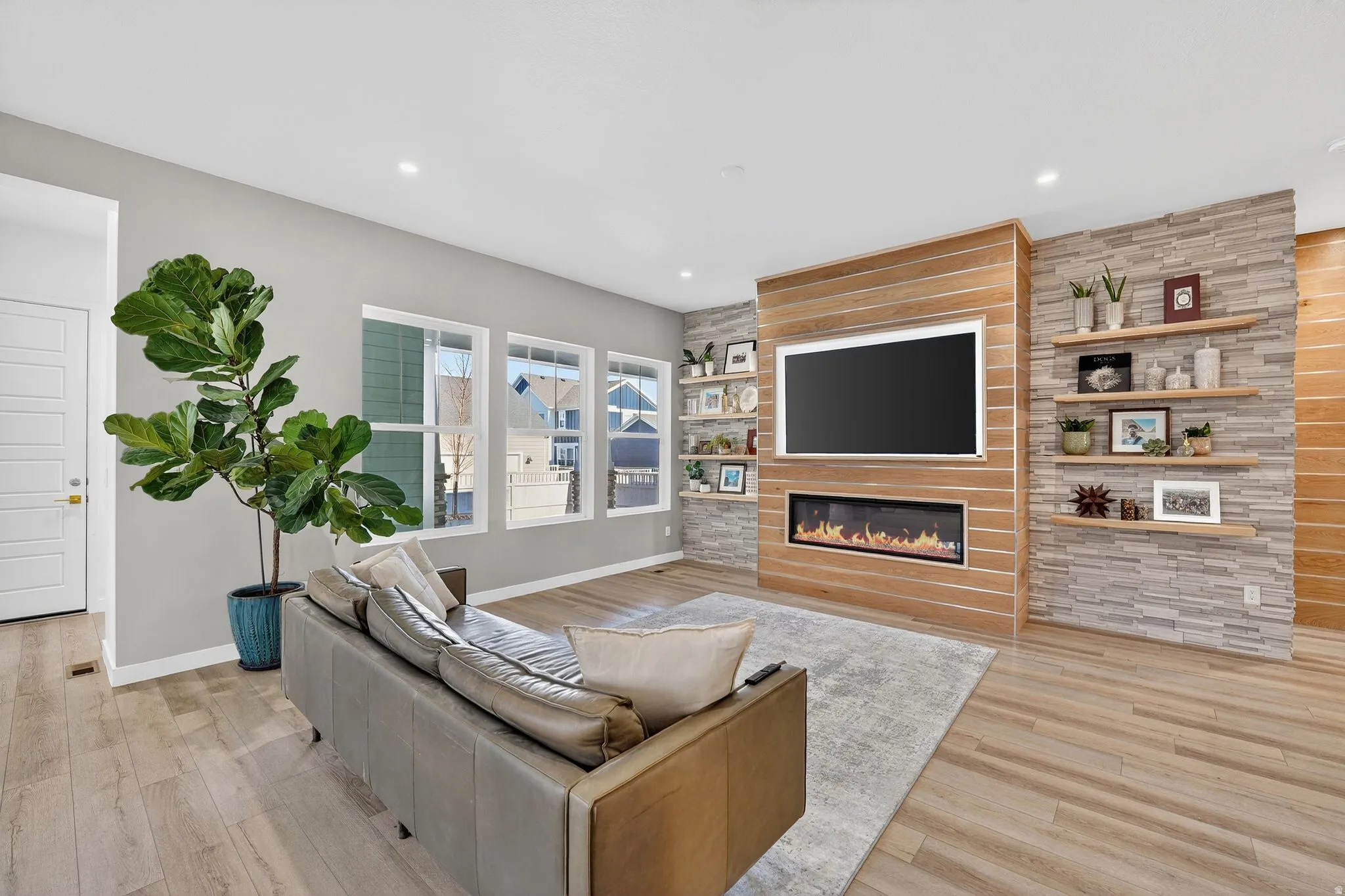 Living room with stone accent wall upgrades, floating shelves, fireplace and included TV
