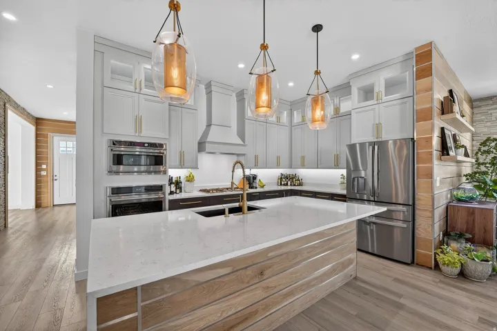 Chefs Kitchen with upgraded lighting, cabinets, wood accents and oversized waterfall granite island