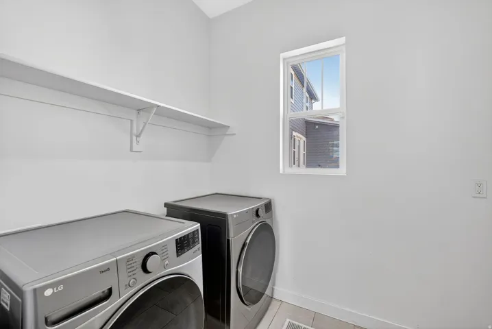 Washroom with separate washer and dryer and tile patterned flooring