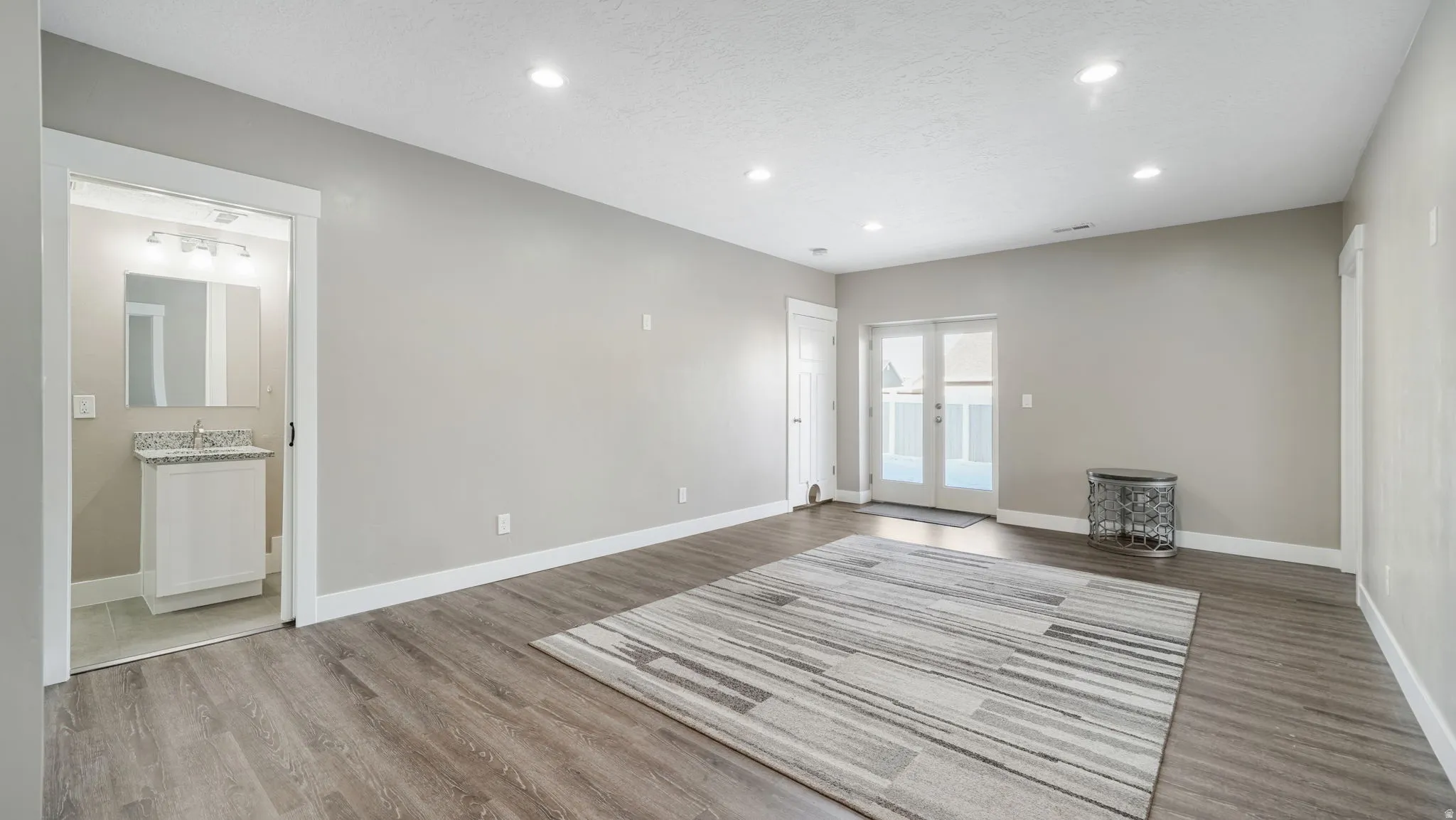 Unfurnished living room with recessed lighting, french doors, light wood finished floors, and a textured ceiling