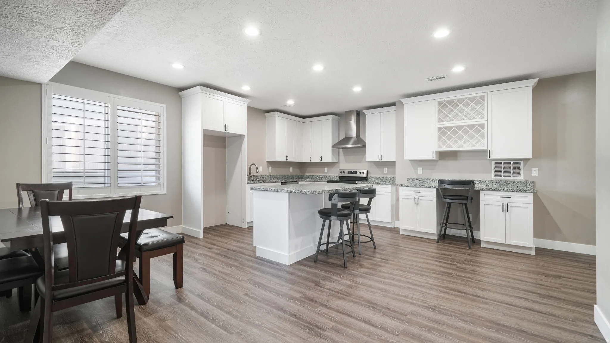 Kitchen with a breakfast bar area, white cabinetry, a textured ceiling, recessed lighting, and light stone countertops