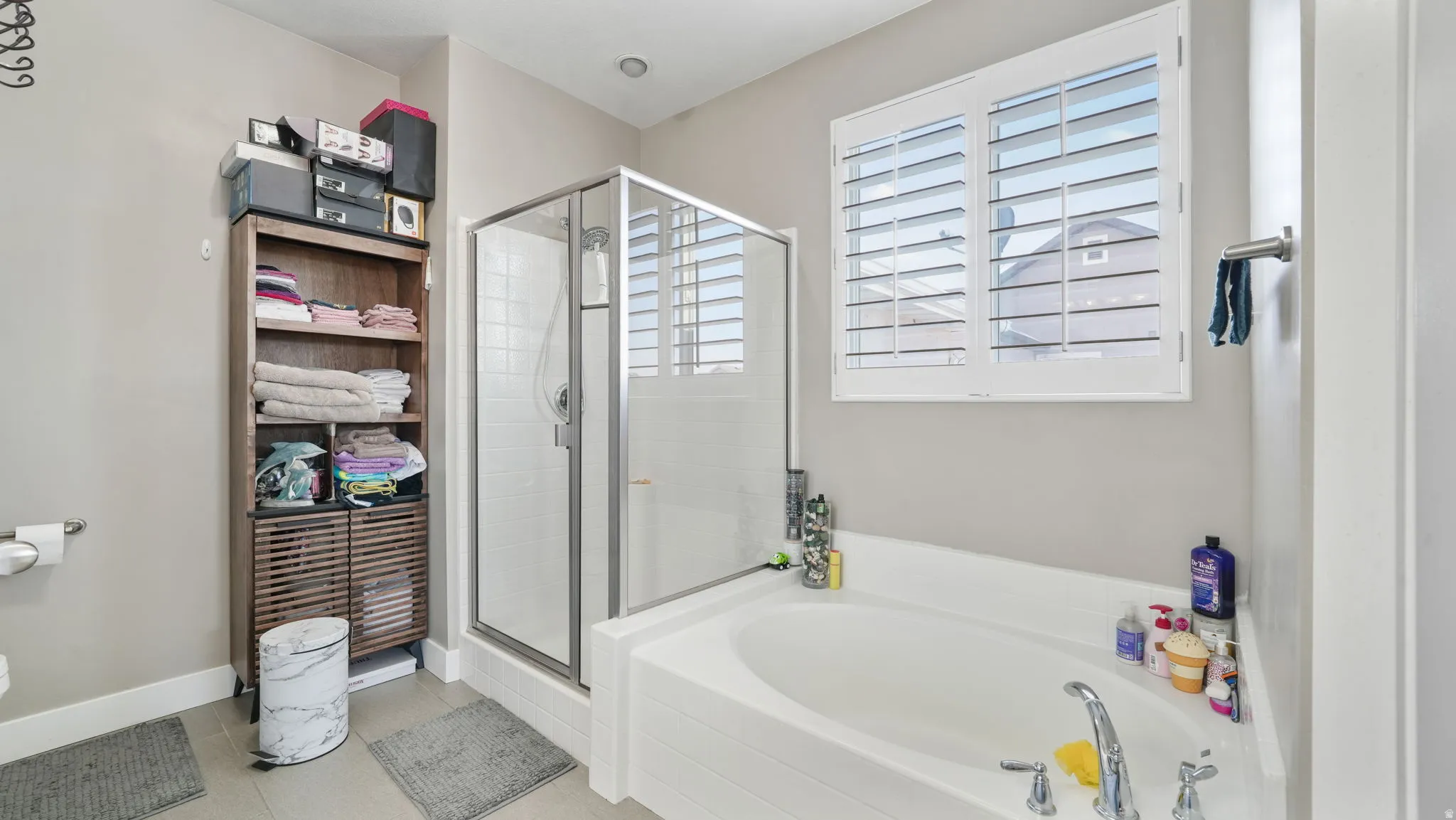 Full bath with light tile patterned floors, a shower stall, and a bath
