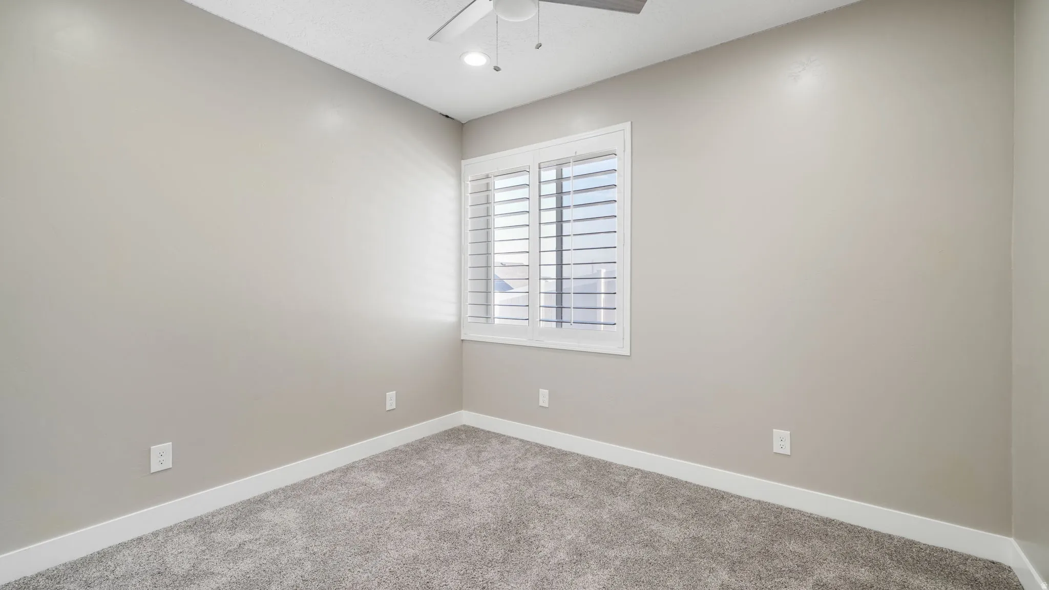Carpeted empty room with baseboards and a ceiling fan