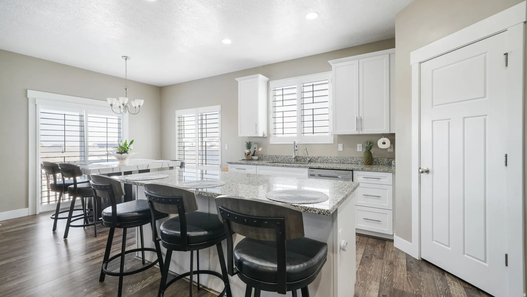 Kitchen featuring a center island, a breakfast bar, healthy amount of natural light, white cabinetry, and a textured ceiling