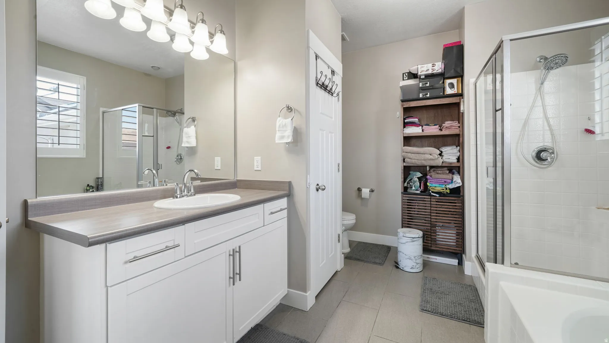 Full bath featuring vanity, a shower stall, a bathtub, light tile patterned floors, and a closet