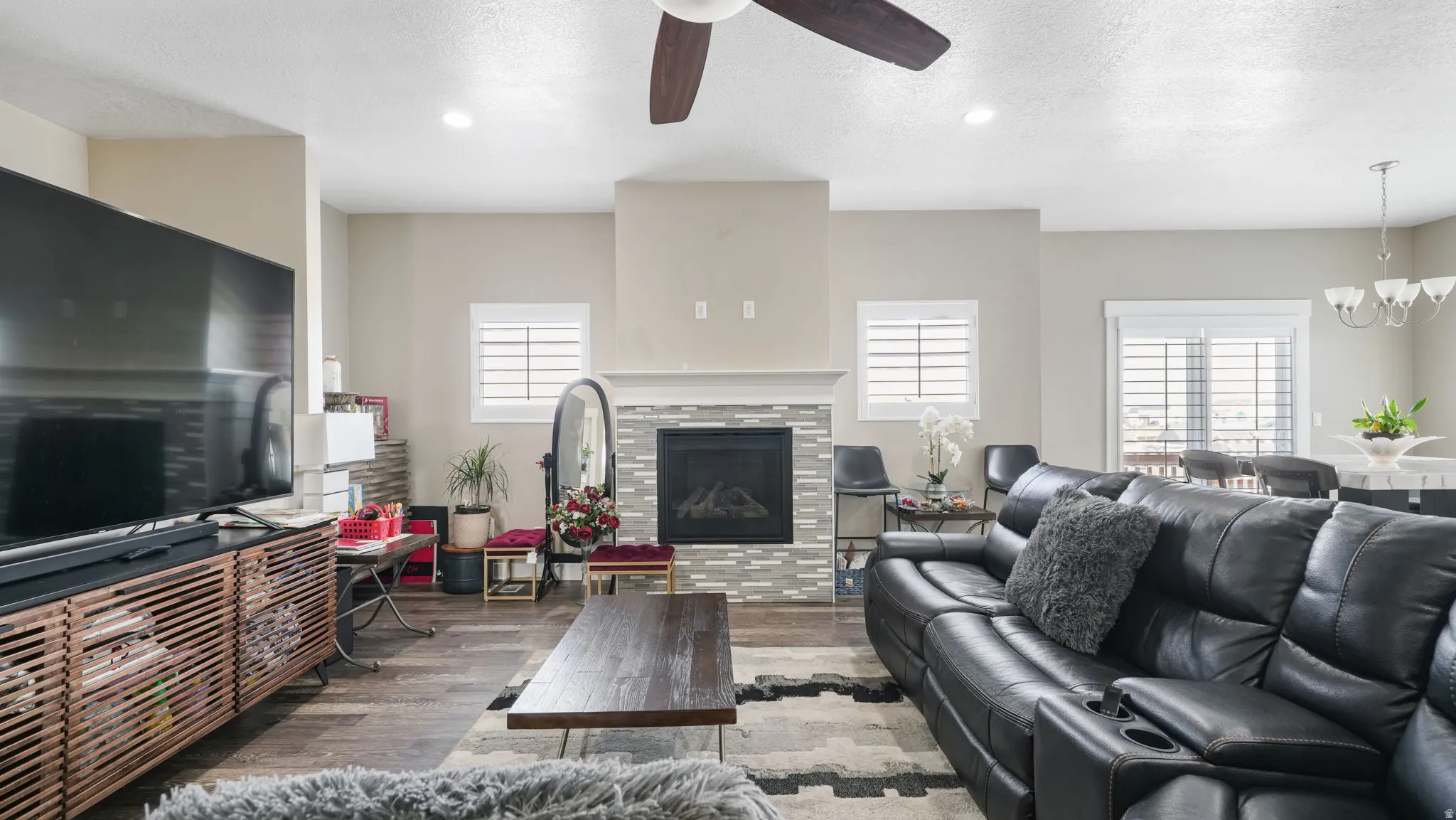 Living room with wood finished floors, plenty of natural light, a textured ceiling, a tiled fireplace, and recessed lighting