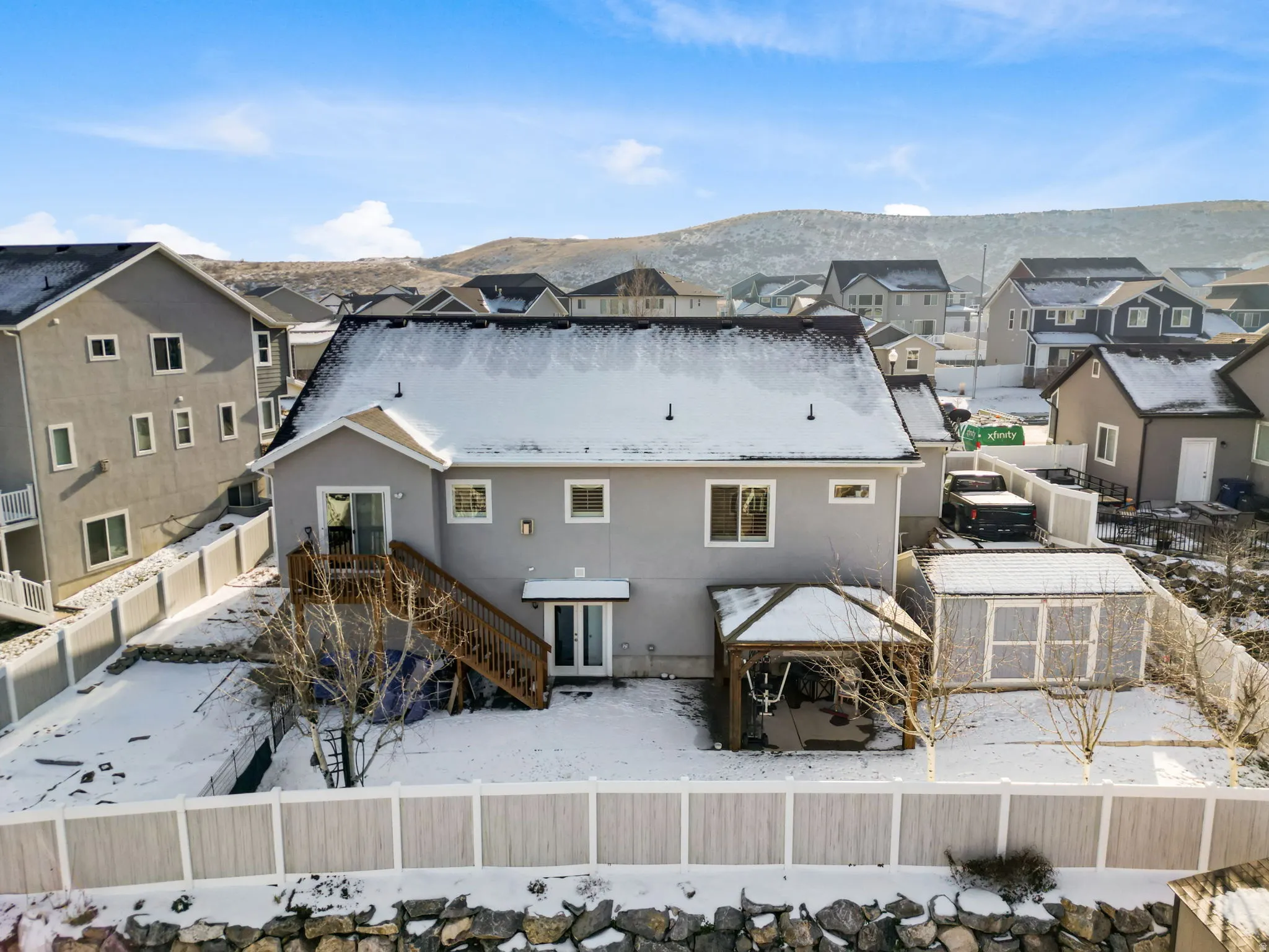 Snow covered house featuring a fenced backyard, a residential view, stairs, and stucco siding