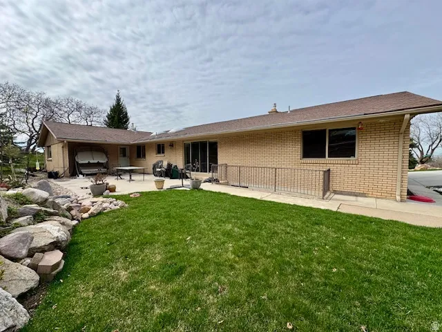 Back of property with a patio, brick siding, and a lawn