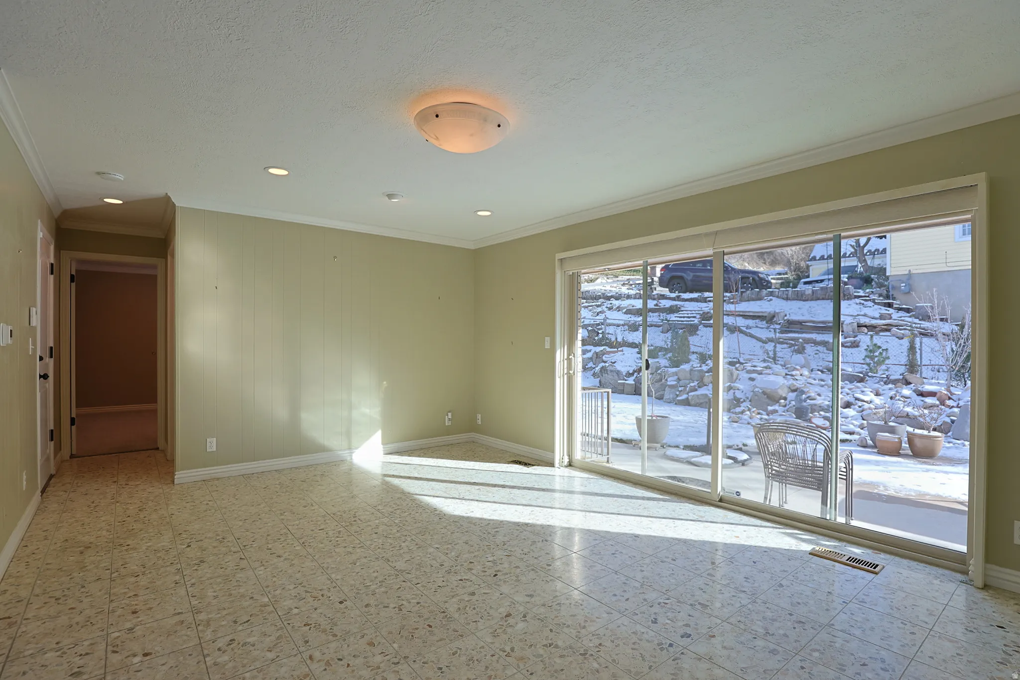 Spare room featuring light floors, crown molding, and a textured ceiling